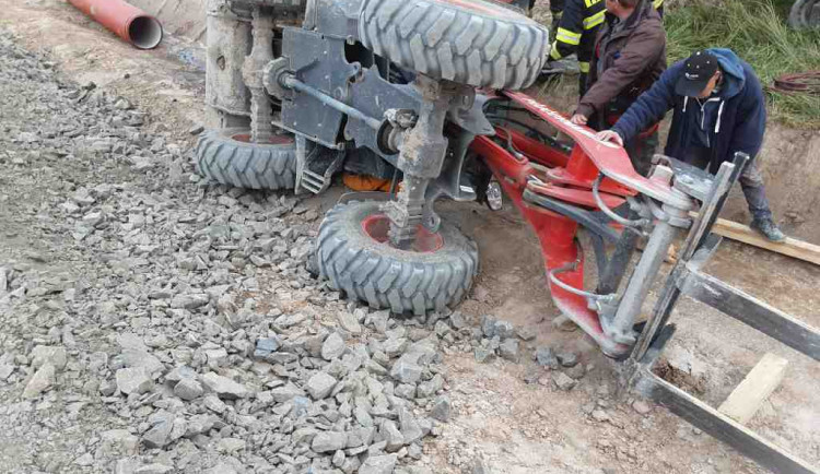 Převrácený nakladač zavalil dělníka, vyprostit ho museli hasiči.