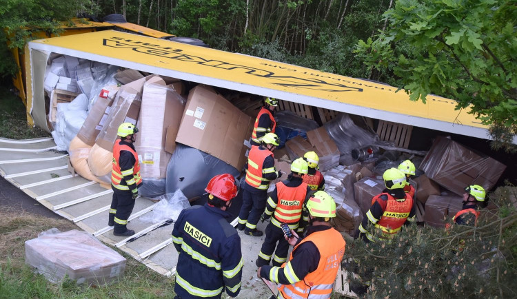 Kamion převážející nebezpečné látky skončil po střetu s osobákem převrácený mimo vozovku