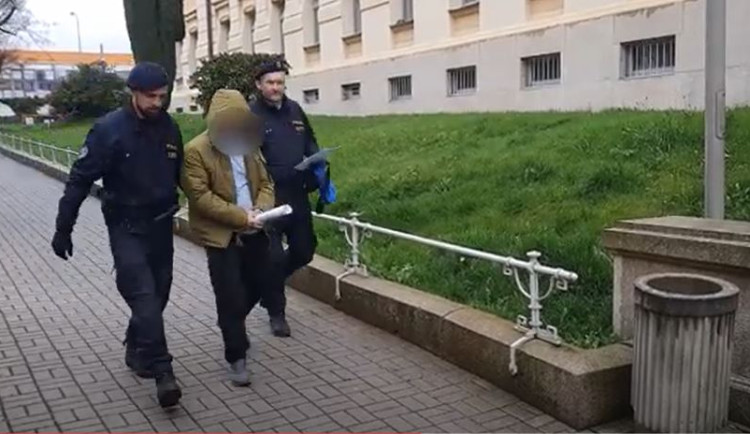 Policisté eskortují k soudu staršího z dvojice útočníků, který pak putoval do vazby