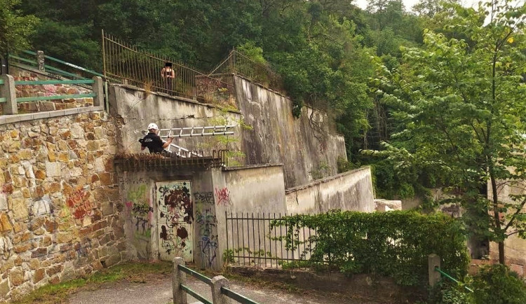 Strážník s žebříkem se snaží dostat do míst, kam spadlo sluchátko. Nahoře situaci sleduje nešťastná slečna